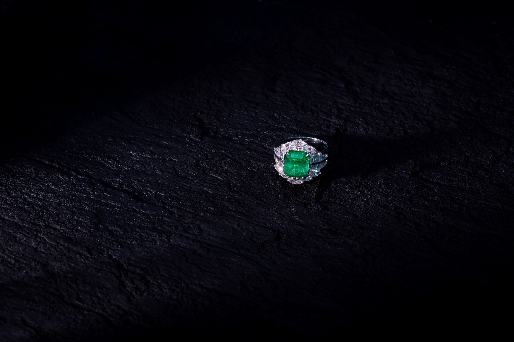 no oil Colombian emerald and diamond ring against a dark background — emerald treatment is assessed by clarity modification grade, not heat treatment, JUSTLEE collection